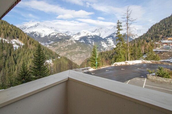 A mountain view from a balcony with a parking area in the foreground.