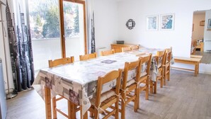 A dining area with a long table and chairs, a window with curtains, and a small cabinet. - 70m from ski slopes, 1st floor, view mountain, parking, tv, ski locker, 46m², Valfréjus (Valfréjus)