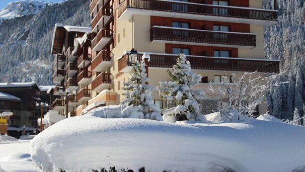 A multi-story hotel with balconies, snow-covered trees, and a mountainous backdrop. - 70m from ski slopes, 1st floor, view mountain, parking, tv, ski locker, 46m², Valfréjus (Valfréjus)