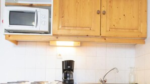 A compact kitchen with a microwave, coffee maker, dishwasher, and wooden cabinets. - 70m from ski slopes, 1st floor, view mountain, parking, tv, ski locker, 46m², Valfréjus (Valfréjus)