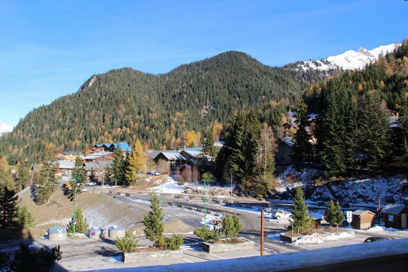 A mountainous area with a ski resort, including buildings, trees, and a parking area.