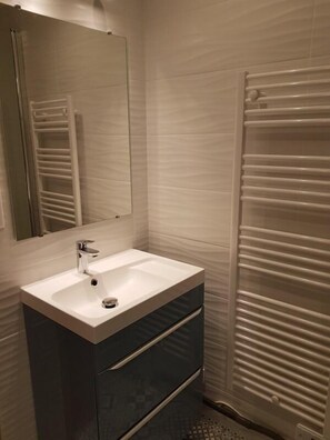 A modern bathroom with a white sink, a mirror, and a towel rack. - 20m from ski slopes, 2nd floor, tv, ski locker, 21m², Montgenèvre (Montgenèvre)