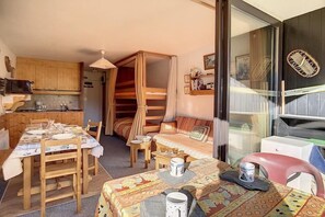Ett litet rum med en våningssäng, ett matbord och ett litet kök.