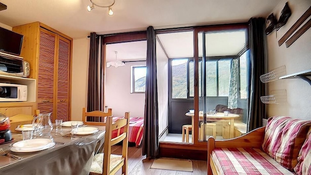 Une pièce compacte comprenant une table à manger pour quatre personnes, un canapé, un lit et une kitchenette équipée d’un four à micro-ondes et d’un grille-pain.