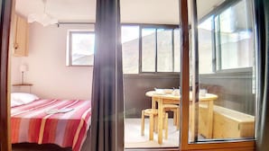 Une chambre à coucher avec un lit, une petite table avec des chaises et une fenêtre.