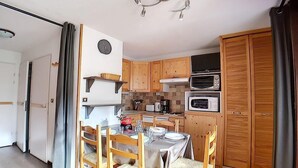 Une cuisine compacte dotée de meubles en bois, d’un four à micro-ondes, d’une cuisinière et d’un coin repas avec une table et des chaises.