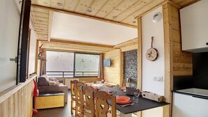 Un espacio habitable compacto con comedor, cocina y un ventanal grande.