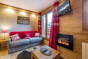 Ein gemütliches Wohnzimmer mit einer Couch, einem Kamin und einem Fernseher.