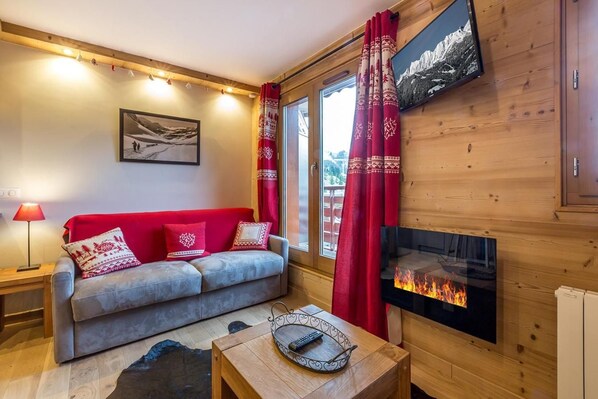 A cozy living room with a sofa, a fireplace, and a television.