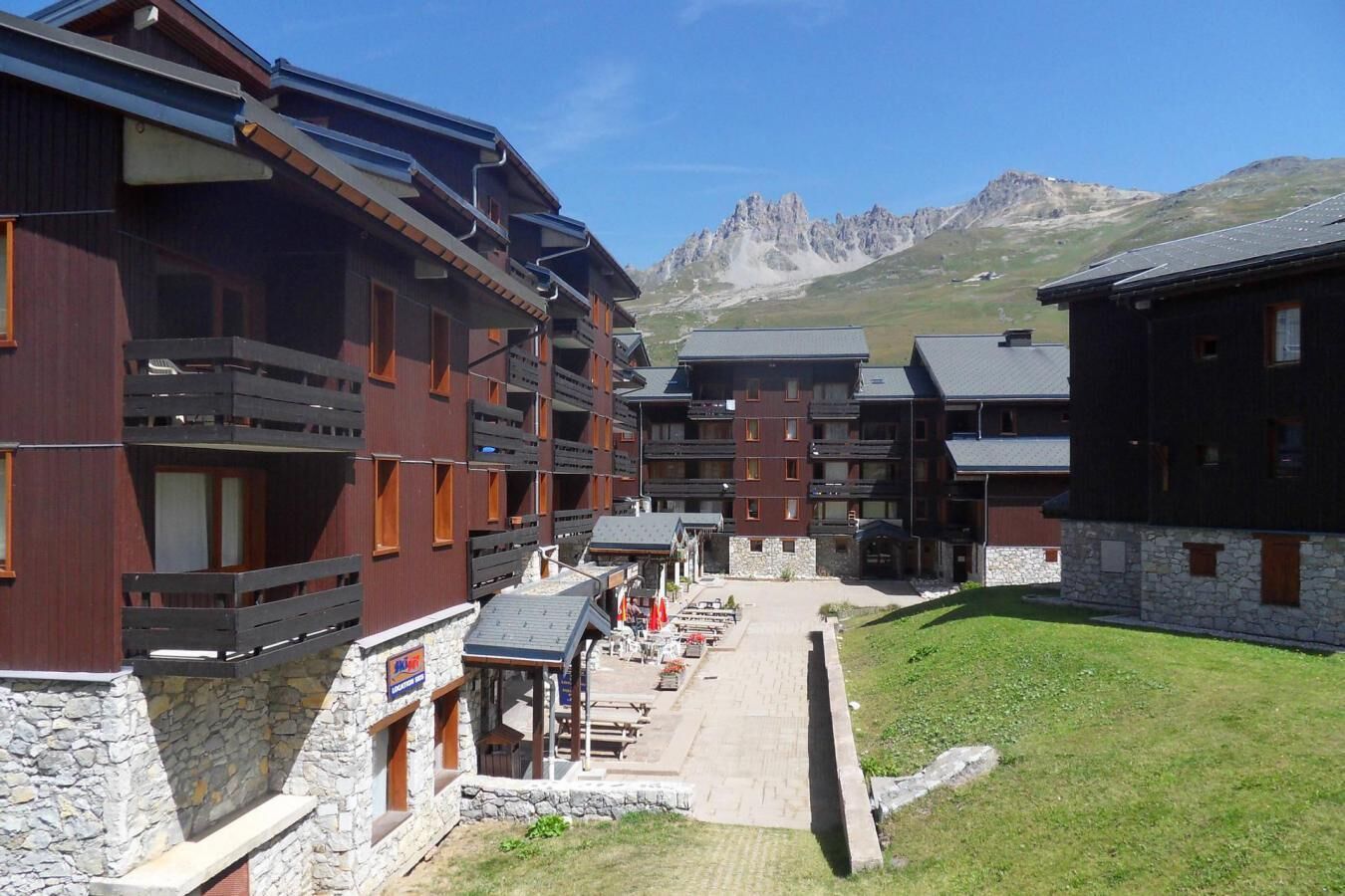 Un hotel de diversos pisos amb balcons, parets de pedra i vistes a les muntanyes.