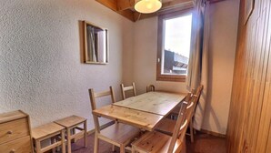 Une pièce comprenant une table à manger en bois, six chaises, un petit meuble en bois et une fenêtre avec des rideaux.