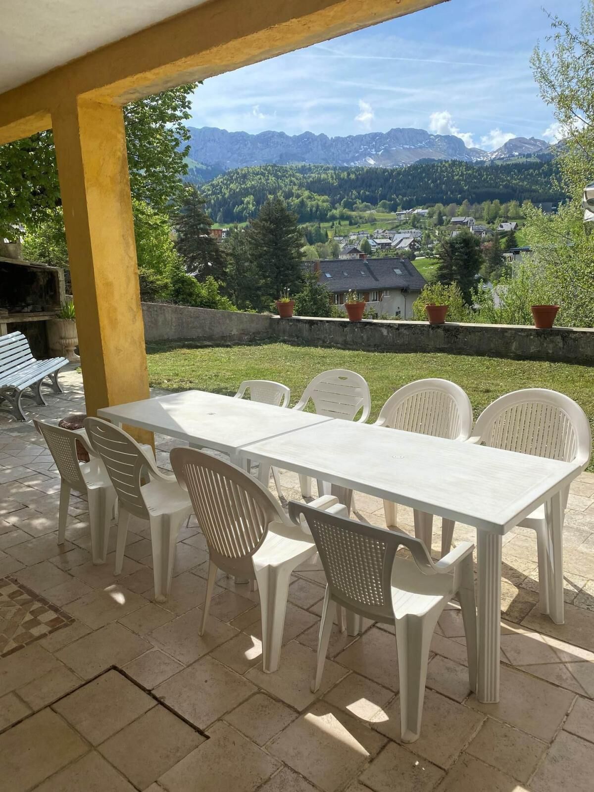 A covered patio with a table and chairs, overlooking a mountainous landscape.