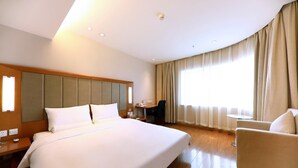Une chambre d’hôtel avec un grand lit, un bureau, une chaise et une petite table.