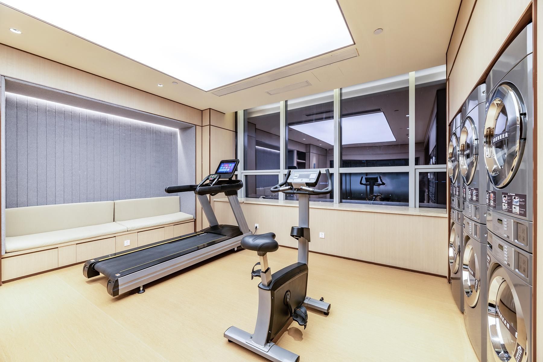Un gimnasio con cinta de correr, elíptica y bicicletas estáticas.