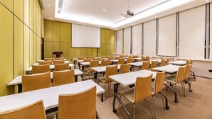 Une salle de conférence équipée de tables et de chaises, d’un projecteur et d’un écran.