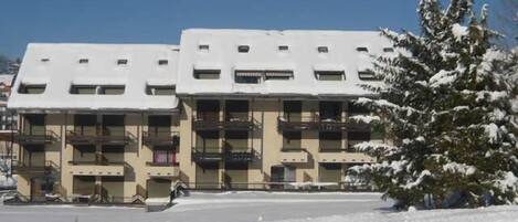 Un edificio de varios pisos con balcones, rodeado de nieve.