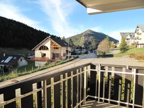 A residential area with a house featuring a sloped roof and a balcony, surrounded by a wooden fence and a mountain in the background. - Ground floor, balcony, tv, 33m², Villard de Lans (Villard-de-Lans)