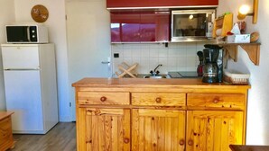 A kitchen with a wooden cabinet, a microwave, and a refrigerator. - 3rd floor, view mountain, balcony, tv, 33m², Villard de Lans (Villard-de-Lans)