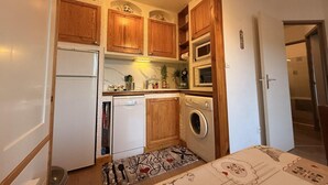 Uma cozinha compacta com armários de madeira, geladeira, lava-louças e máquina de lavar.