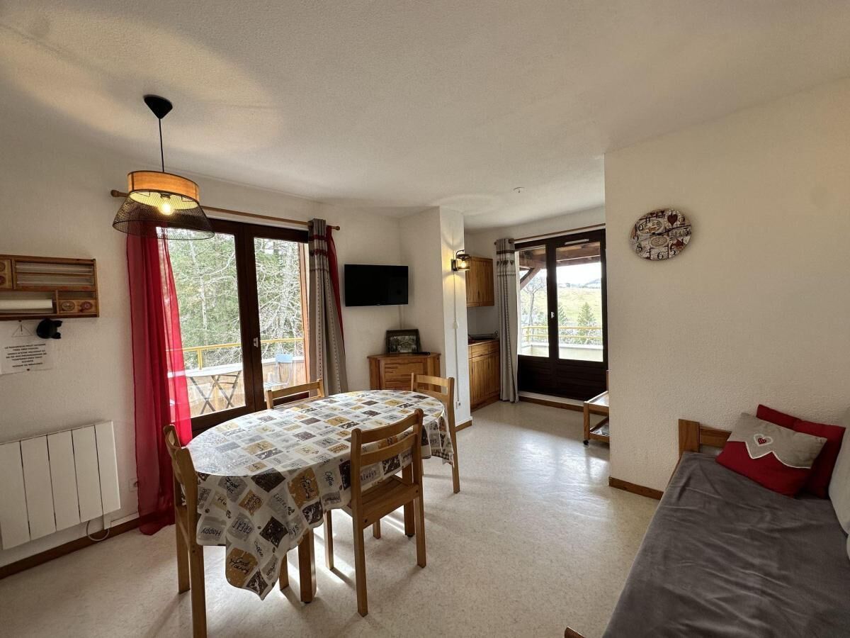 A cozy room with a dining table, chairs, a bed, and a TV.