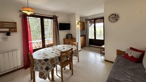 Ein gemütliches Zimmer mit Esstisch, Stühlen, einem Bett und einem Fernseher.