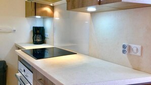 A compact kitchen with a built-in stovetop, a coffee maker, and a single electrical outlet.