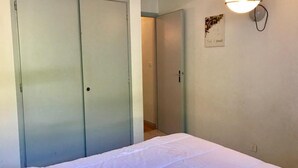 A bedroom with a bed, a wardrobe, and a wall-mounted light fixture.