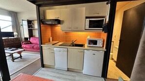 Cocina compacta con microondas, lavavajillas y fregadero.