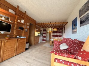 A wooden interior with a sofa, TV, and kitchen area.