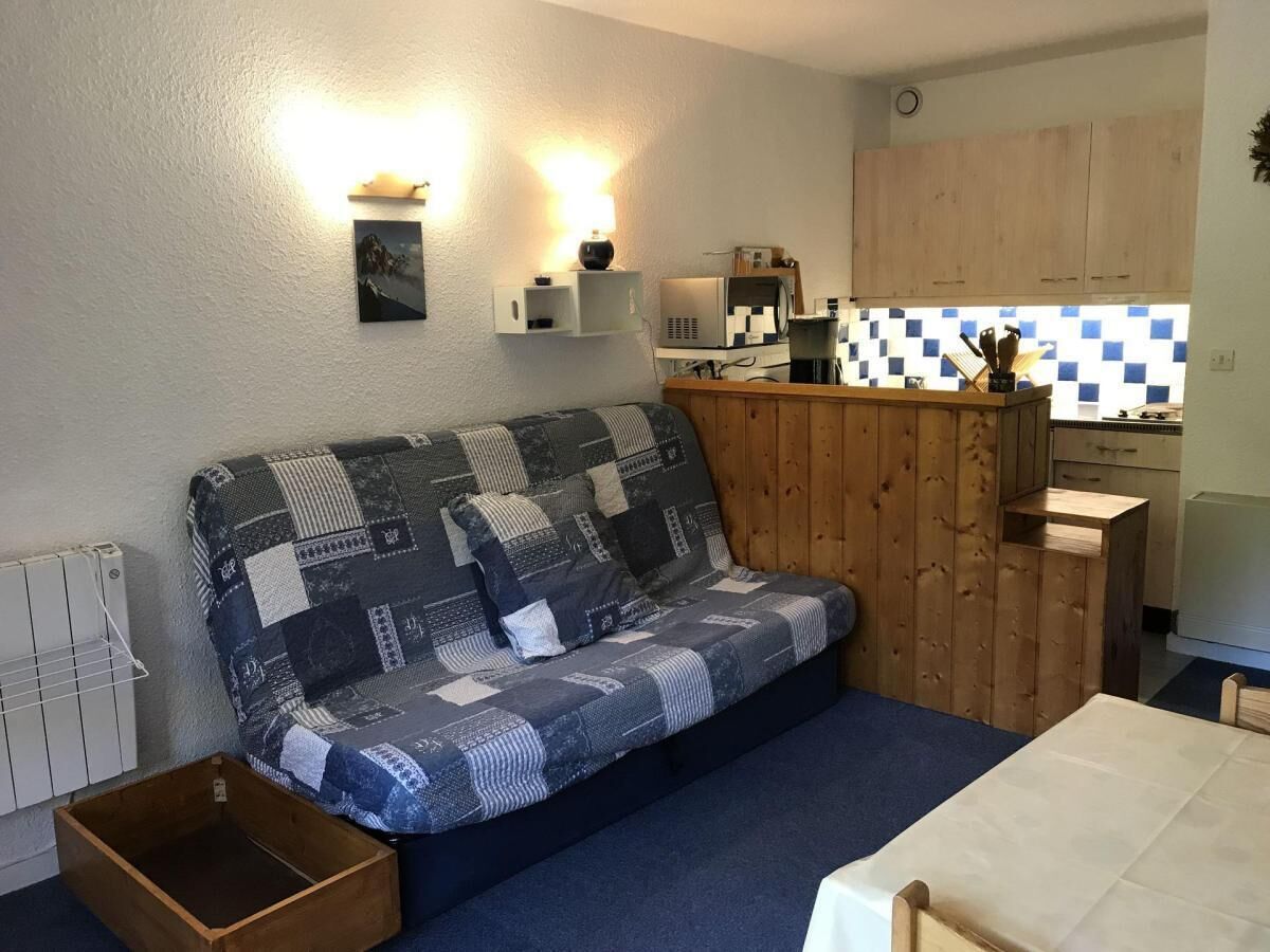 A compact living space with a patchwork sofa, a small kitchen area, and a dining table.