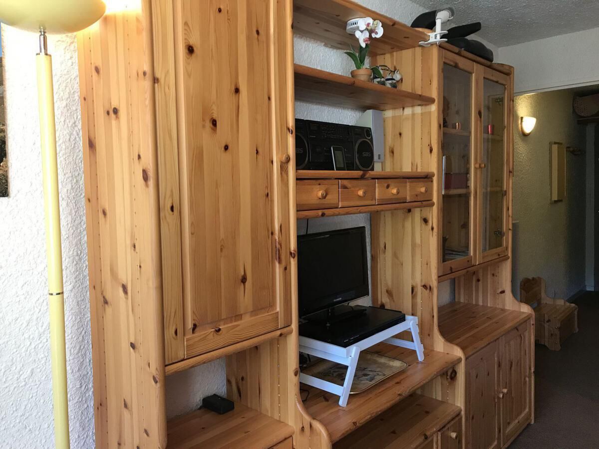 Un meuble de rangement en bois comprenant un téléviseur, une radio et des tiroirs.