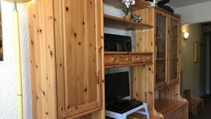 Un mueble de madera con televisión, radio y cajones para guardar objetos.