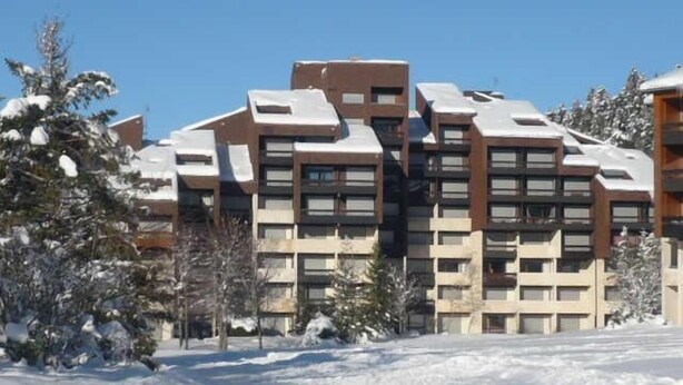 Un edificio moderno de varios pisos con techo plano, rodeado de árboles cubiertos de nieve.