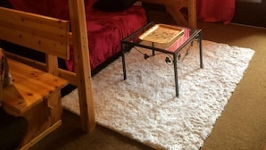Una habitación acogedora con una cama litera de madera, un sofá rojo y una pequeña mesa.