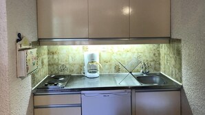 Una cocina compacta con estufa, cafetera y lavamanos.