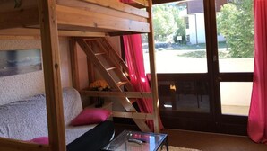 Una habitación acogedora con literas, una mesita de vidrio y vistas al exterior.