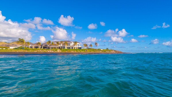 Une propriété située en bord de mer, comprenant plusieurs maisons, une plage de sable et l’océan.
