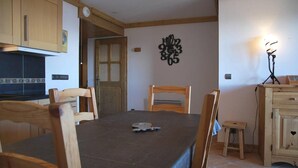 A dining area with a table, chairs, and a small stool. There is a clock on the wall and a decorative wall piece above the table. - 50m from ski slopes, 3rd floor, view panoramic, swimming pool, balcony, tv, ski locker, 46m² (Bourg-Saint-Maurice)