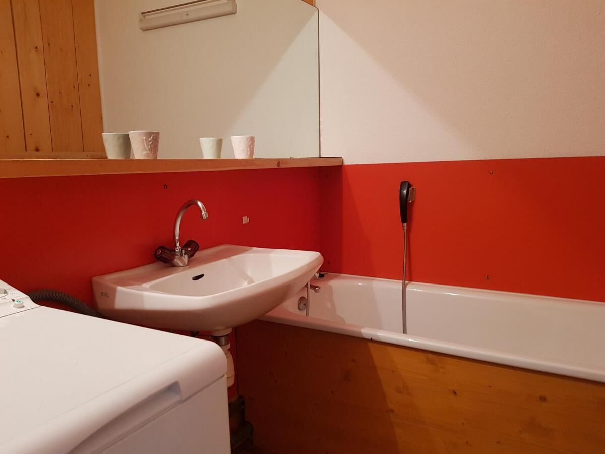 A bathroom with a white sink, a bathtub, and a wooden vanity.