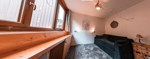 A cozy room with a wooden bench, a dark sofa, a small table, and a wall-mounted light fixture. - 7th floor, tv, 13m², Les Arcs (Les Arcs)