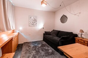 A cozy living room with a dark sofa, a wooden coffee table, and a rug. There's a wall-mounted mirror and a framed picture on the wall. - 7th floor, tv, 13m², Les Arcs (Les Arcs)