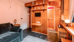 Ett mysigt rum med träinredning, en soffa, ett litet bord och en tv som är monterad på väggen.