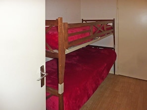 A bunk bed with a metal frame and red bedding in a room with a wooden floor and white walls. - Ski-in/ski-out & foot of the slopes, 3rd floor, view ski slopes, balcony, tv, 60m², Les Orres (Les Orres)