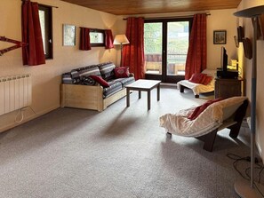 Een gezellige woonkamer met een bank, een stoel, een tafel en een radiator.