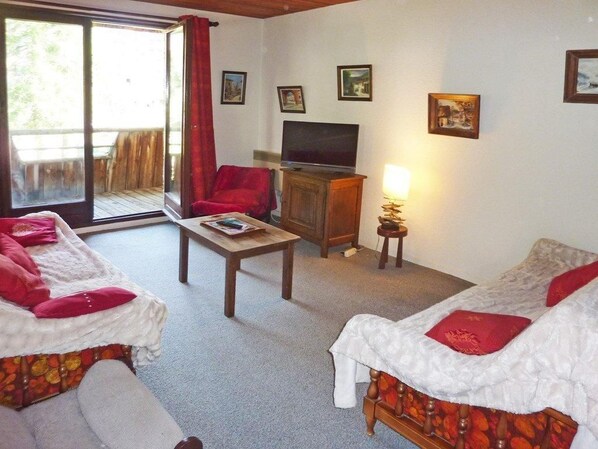 A room with two beds, a television, a table, and a chair.