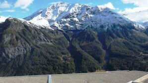 A mountain landscape with snow-capped peaks and dense forested valleys.