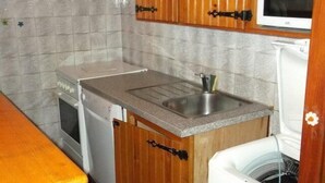 A compact kitchen with wooden cabinets, a built-in microwave, a sink, and a dishwasher.
