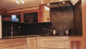 A compact kitchen with wooden cabinets, a stainless steel range hood, and a black countertop. - Floor -1, terrace, tv, ski locker, 70m², Val Cenis (Lanslevillard)