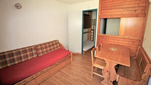 Ein gemütlicher Raum mit einem Holzbett, einer karierten Couch und einem Holztisch.