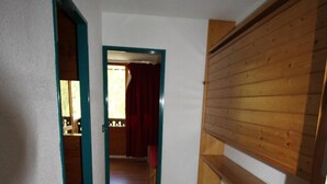 Ein schmaler Raum mit einem hölzernen Etagenbett, einer weißen Matratze und einem Holzschrank.